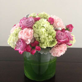 Pink and lavender flowers arranged in a green glass vase