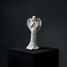 White angel figurine holding a red cardinal with memorial text