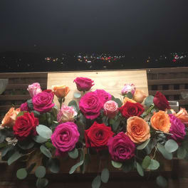 Arrangement of multicolored roses with eucalyptus on a wooden ledge