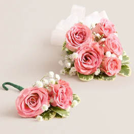 Two pink rose boutonnieres with white baby's breath and ribbon