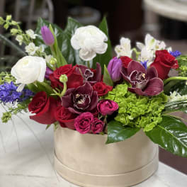 Mixed bouquet of red and white roses with orchids in a beige box