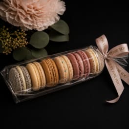 Wrapped macarons with a pale flower and ribbon on a black background