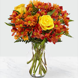 Bouquet of yellow roses and orange alstroemeria in a clear glass vase