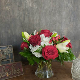 Bouquet of red roses, white lilies, and white carnations in a glass vase