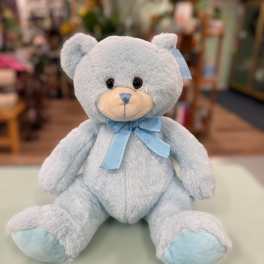 Light blue teddy bear with a ribbon bow sitting on a counter