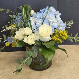 Blue hydrangeas and cream roses in a glass vase