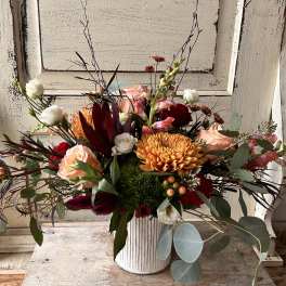 Mixed bouquet in a white ribbed vase with peach, red, and white blooms