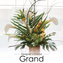 Tall floral arrangement with white calla lilies and tropical foliage in a vase