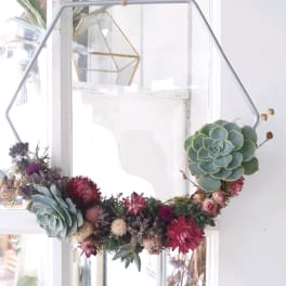 Succulent wreath with pink and purple dried flowers on a metal frame