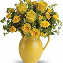 Yellow roses arranged in a yellow ceramic pitcher vase