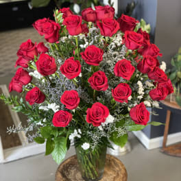 Bouquet of red roses in a glass vase with white filler flowers