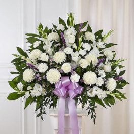 White funeral spray with a lavender ribbon on a stand