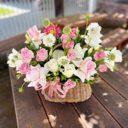 Pink and white flowers arranged in a wicker basket