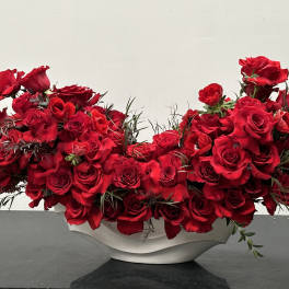 Red roses arranged in a white bowl vase