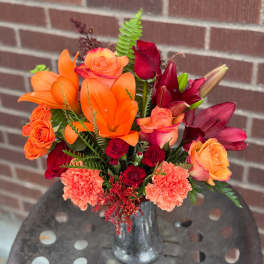 Bouquet of orange and red flowers in a silver vase