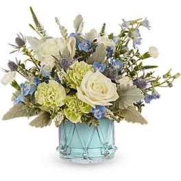 White and blue floral arrangement in a light blue glass vase