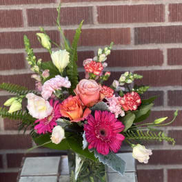 Mixed pink and peach bouquet in a square glass vase