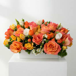 Orange, pink, yellow, and white roses in a white rectangular vase