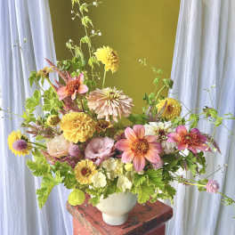 Mixed bouquet of pink, yellow, and white flowers in a white vase