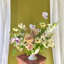 Mixed bouquet of peach roses and small white daisies in a white vase