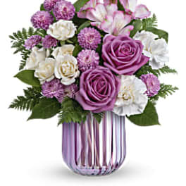 Purple and white flower bouquet in a striped glass vase