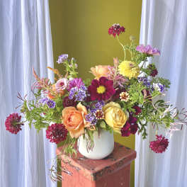 Mixed bouquet in a white vase with pink, yellow, and purple flowers