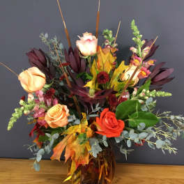 Autumn bouquet of roses and snapdragons in an amber glass vase