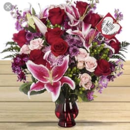 Red roses and pink lilies in a red glass vase with a heart sign