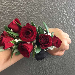 Red rose wrist corsage with greenery and white filler flowers