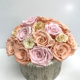 Round bouquet of pastel roses in a textured silver container