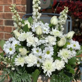 White flowers arranged in a woven basket with green foliage