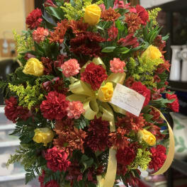 Large bouquet of red, yellow, and orange flowers with a yellow ribbon