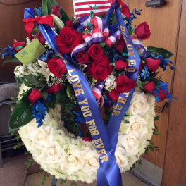 Heart-shaped floral wreath with red and white roses and patriotic ribbons