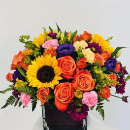 Mixed bouquet with sunflowers, roses, and carnations in a dark vase