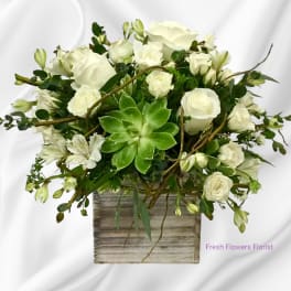 White roses and alstroemeria in a rustic square vase with a green succulent