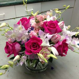 Pink roses and pale orchids arranged in a clear glass vase