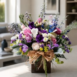 Mixed bouquet of pink, purple, white, and blue flowers in a wooden box