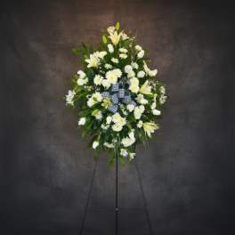 White floral standing spray on an easel with a checkered ribbon
