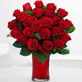 Red roses arranged in a tall red glass vase