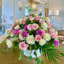 Large arrangement of pink, white, and purple roses in a white vase
