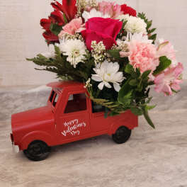 Red truck-shaped flower arrangement with pink, white, and red blooms