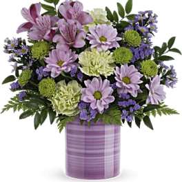 Lavender and green floral arrangement in a purple vase