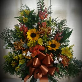 Mixed bouquet with sunflowers and orange blooms tied with a copper ribbon