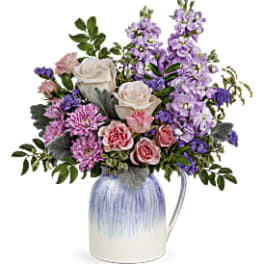 Bouquet of pink and lavender flowers in a blue-and-white pitcher vase
