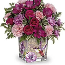 Pink and purple bouquet in a square glass vase with bird artwork