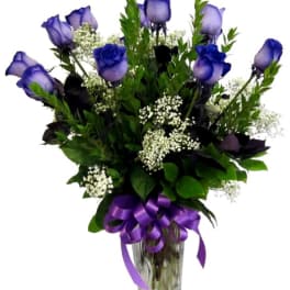 Purple roses in a glass vase with a purple ribbon
