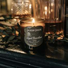 Lit amber candle in a glass jar with a dark label