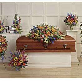 Colorful funeral casket spray with standing floral arrangements around a coffin