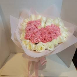 Pink carnations and white roses in pale pink wrapping with a ribbon