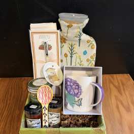 Gift basket with a mug, candles, honey jars, and small accessories